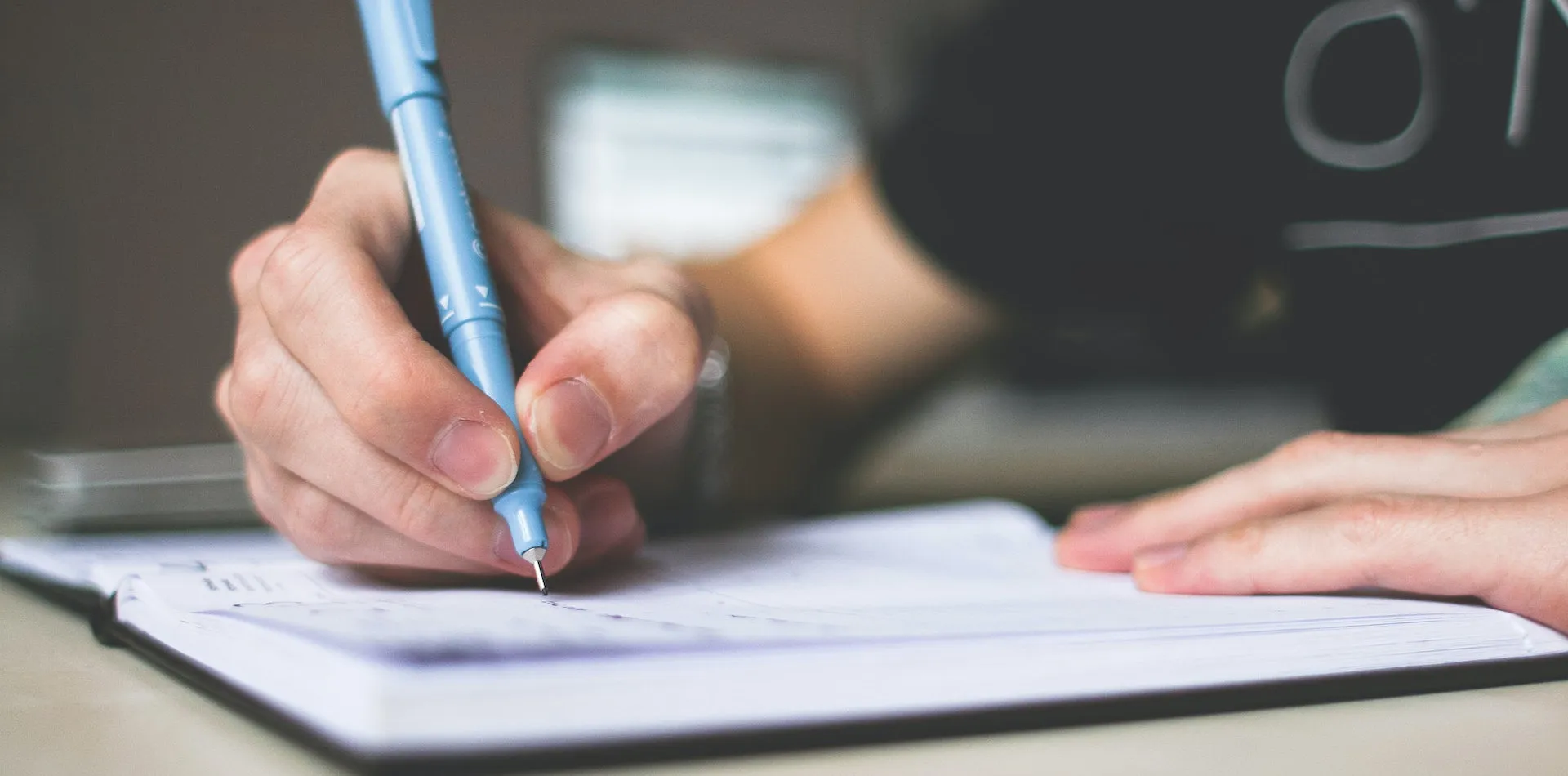 Writing in a notebook with a pen